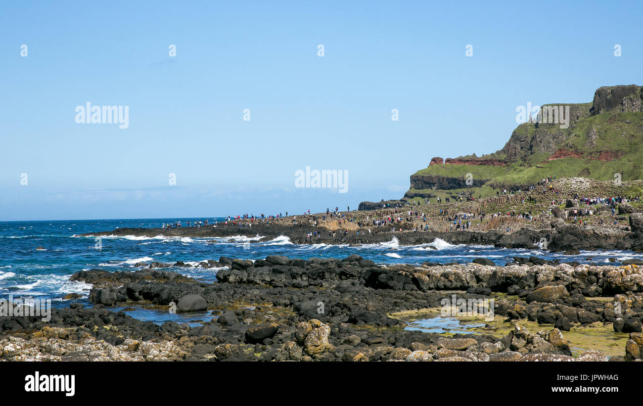 View on the Giant`s Causeway coast stretching out to the Atlantic ocean occupied by tourists and visitors Bushmills Antrim Northern Ireland Stock Photo